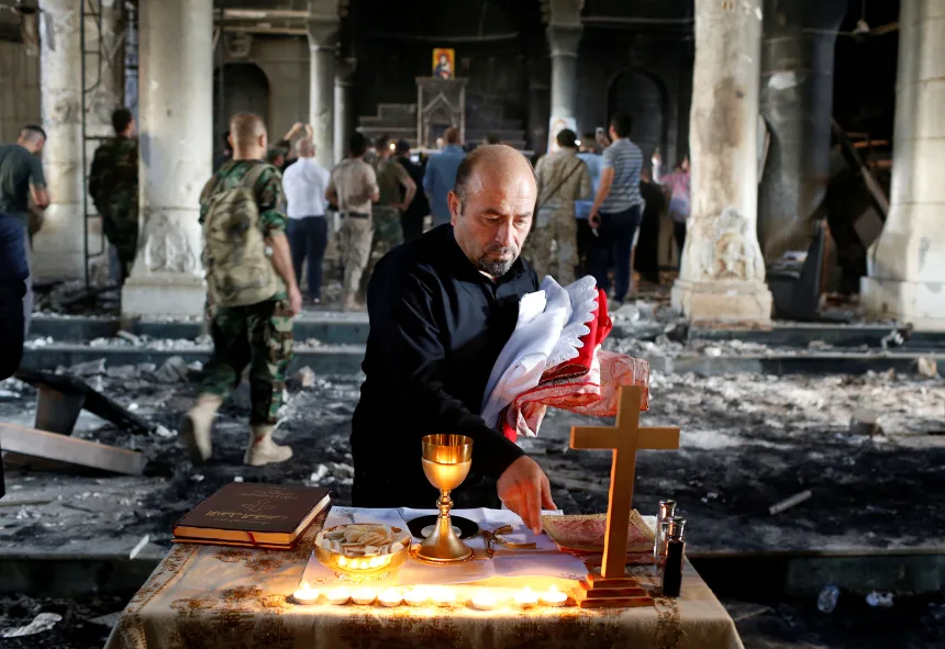 En katolsk prest forbereder et alter i en ødelagt kirke i Irak