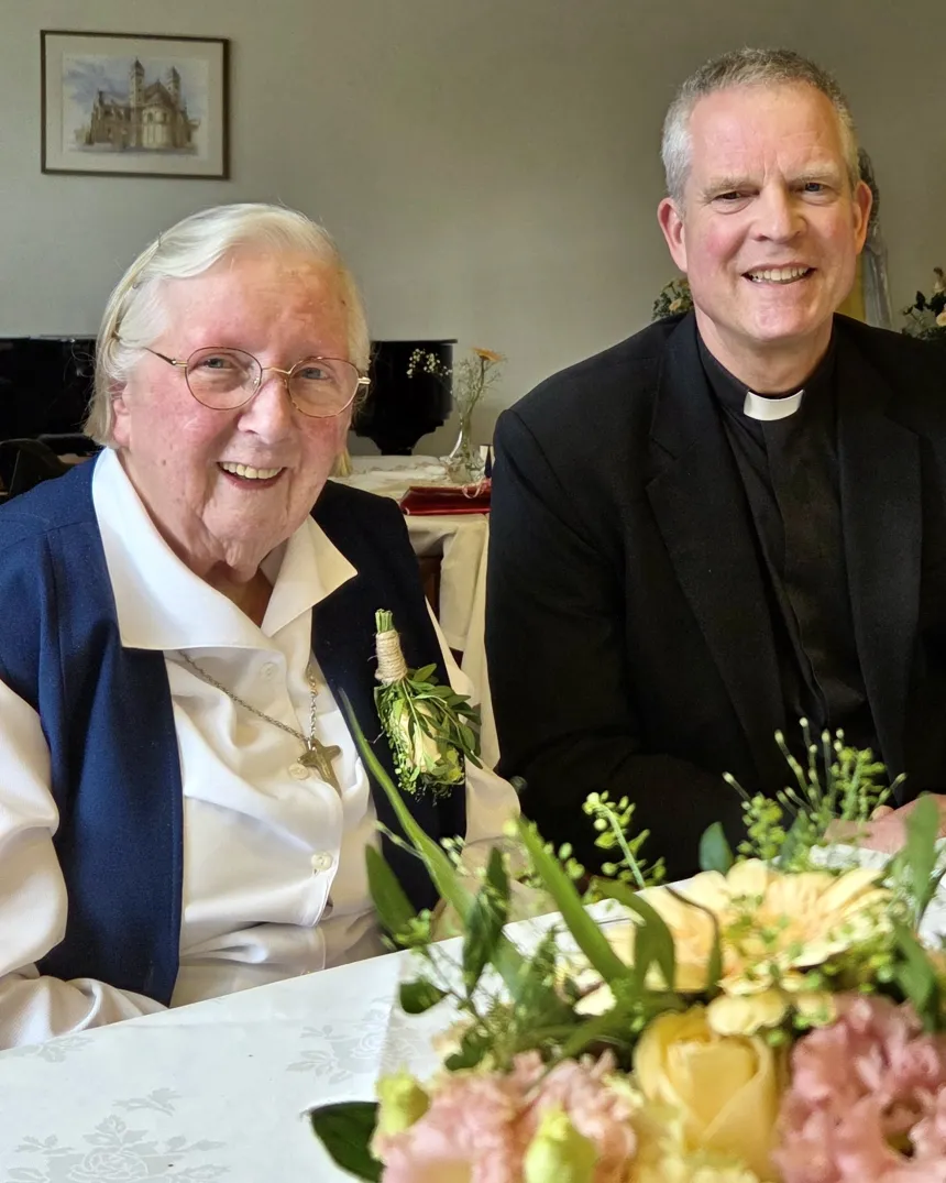 Sr. Hilde Geers og p. Sigurd Markussen ved festpyntet bord. 